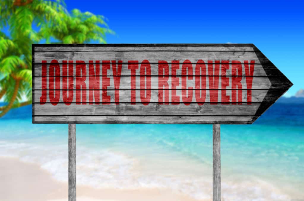 Red Journey to Recovery wooden sign with on a beach background